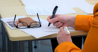 Nainen kirjoittaa muistiinpanoja ruutupaperille.