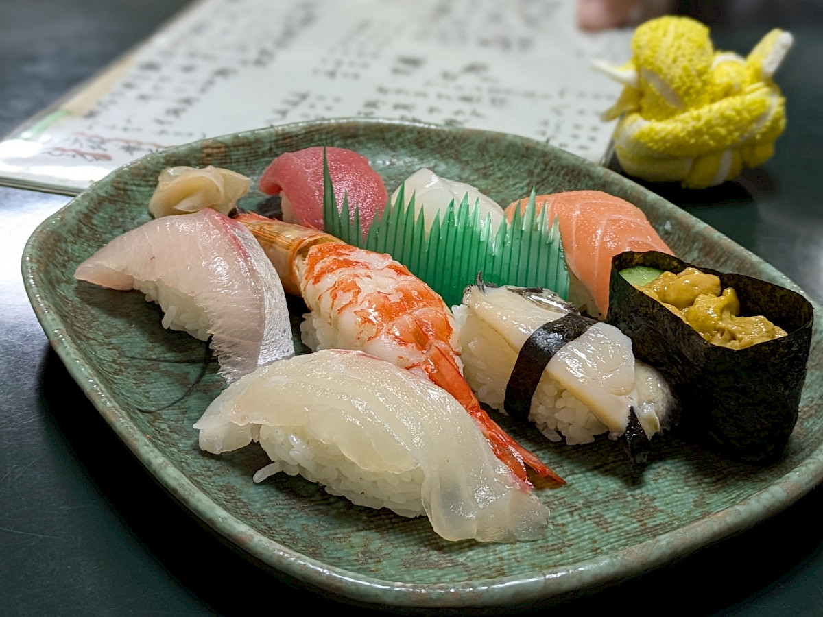 Sushiannoksessa erilaisia kalasusheja vihreällä lautasella.