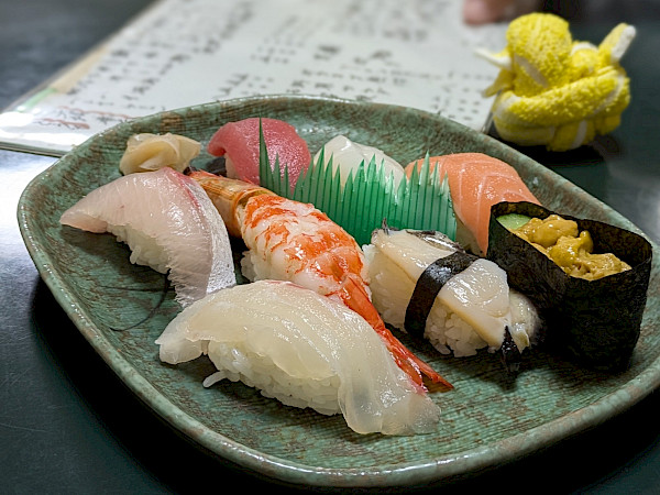 Sushiannoksessa erilaisia kalasusheja vihreällä lautasella.